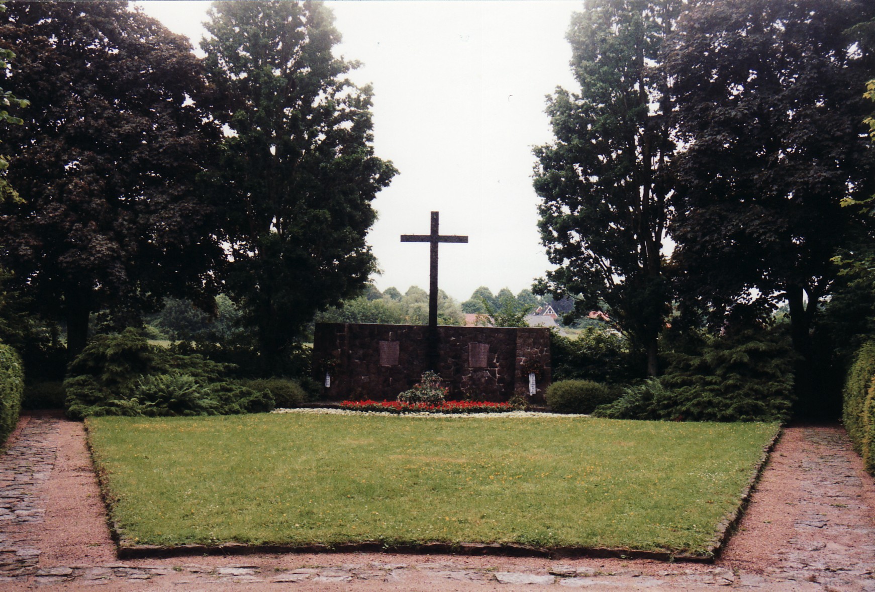 Mur z tablicami upamiętniającymi i krzyżem