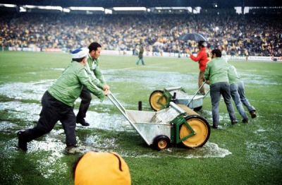 „Wasserschlacht“ vom 3. Juli 1974: Mit Hilfe von Walzen versuchen Stadionhelfer im Frankfurter Waldstadion, das bei einem heftigen Wolkenbruch überschwemmte Spielfeld vom Wasser zu befreien. 