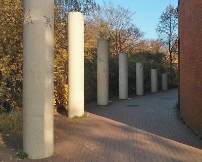 Karol Broniatowski: Säulenreihe am Albert-Einstein-Gymnasium, Berlin-Neukölln, 1989. 9 Säulen, Beton, Höhe 80 bis 650 cm.