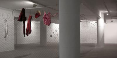 7 METRES, 2005. A room installation. Wire mesh fence, barbed wire, clothing. 300 x 300 cm.