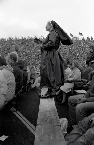Besucherinnen und Besucher der Heiligen Messe - Besucherinnen und Besucher verfolgen die Feier der Heiligen Messe durch den Papst Johannes Paul II. im Gelsenkirchener Parkstadion, 2. Mai 1987. 