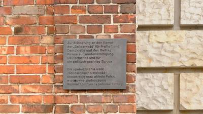 „Zur Erinnerung an den Kampf der Solidarność ... “  - „Zur Erinnerung an den Kampf der „Solidarność“ für Freiheit und Demokratie und den Beitrag Polens zur Wiedervereinigung Deutschlands und für ein politisch geeintes Europa“ – diese Worte zieren die bronzene Gedenktafel auf einem Mauerstück an der Ostseite  