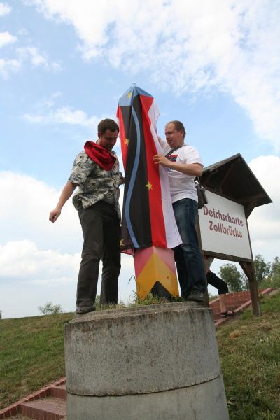 Verhängung des Grenzpfostens mit der Fahne von „Nowa Amerika“. Rechts: Andrzej Łazowski. 